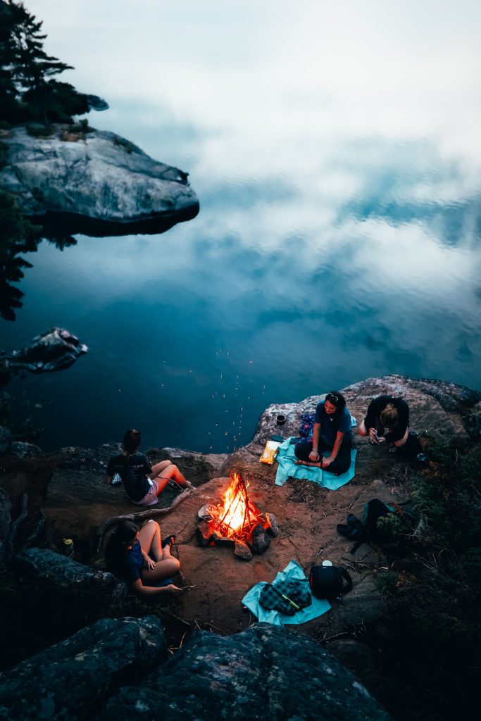 Camping with friends together sitting beside the campfire
