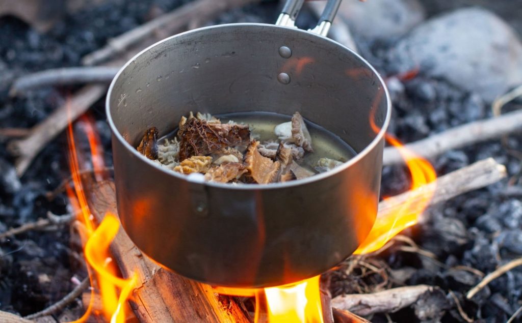 Wild Mushrooms cooking over a campfire using a cooking pot