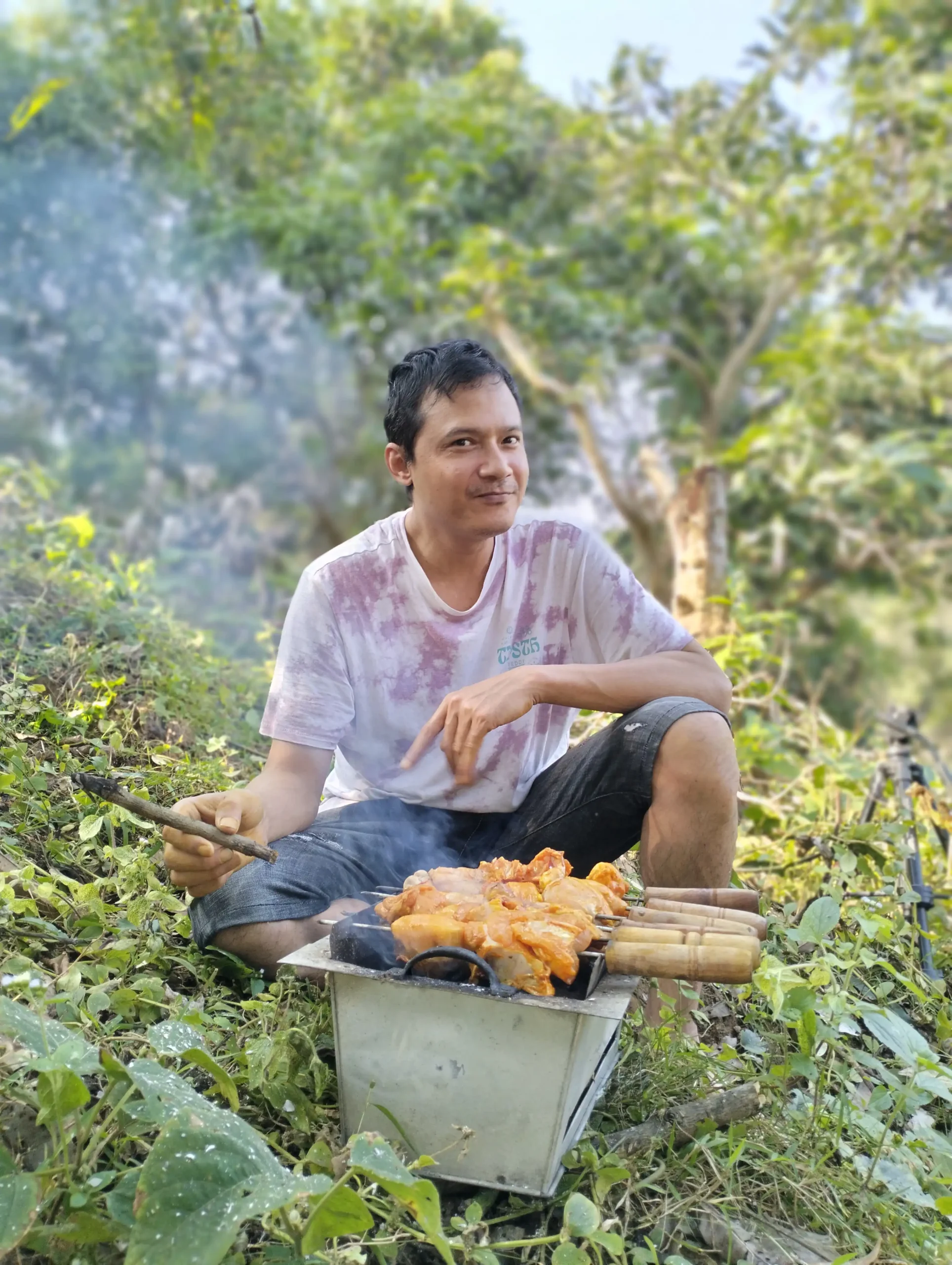 A pot simmering above orange embers at a forest campsite