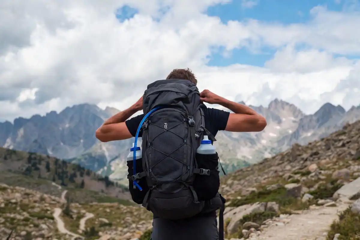 backpacker carrying water bottles and hydration pack