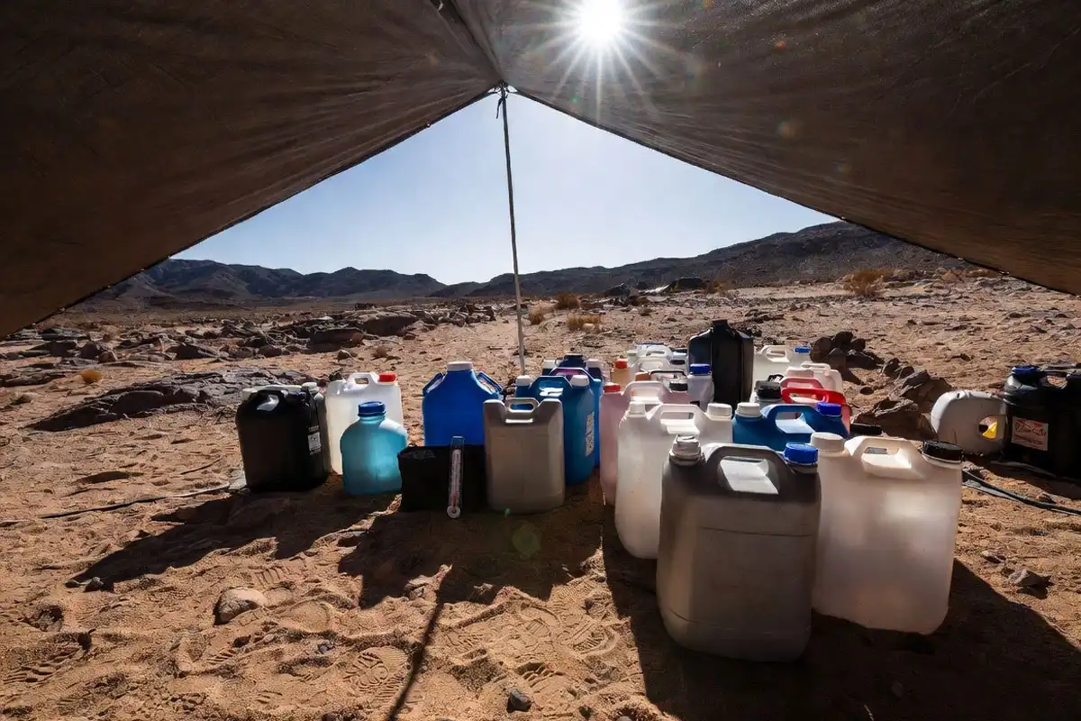 water jugs stored in shade at desert campsite