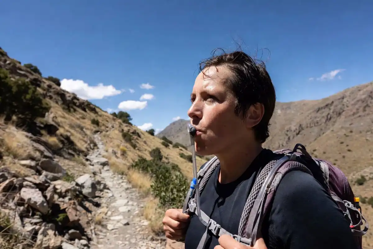 hiker drinking water on sunny trail