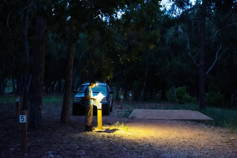 camper choosing a campsite with headlamp at night