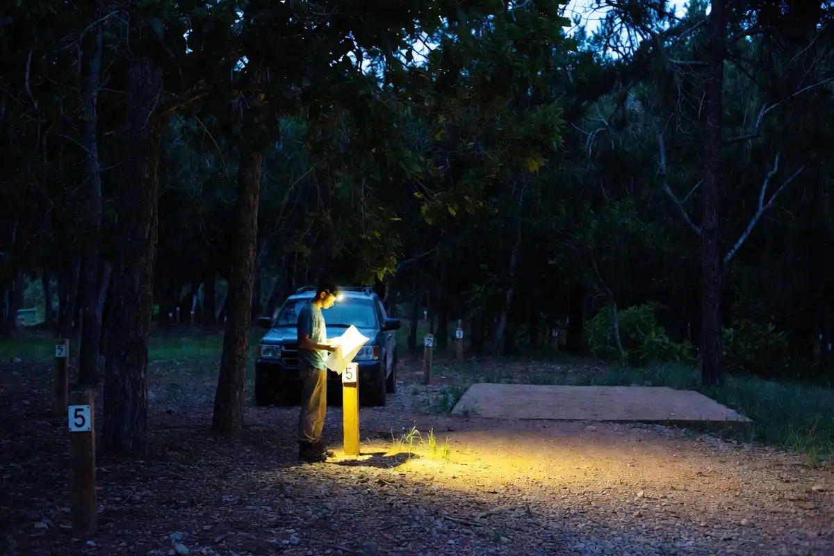 camper choosing a campsite with headlamp at night