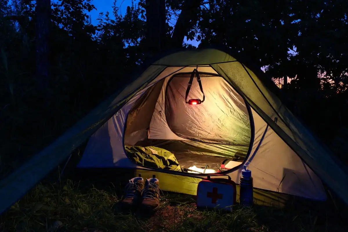 headlamp shoes rain jacket and first aid placed neatly by tent