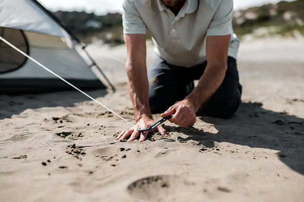 camper tightening guyline after sand settles
