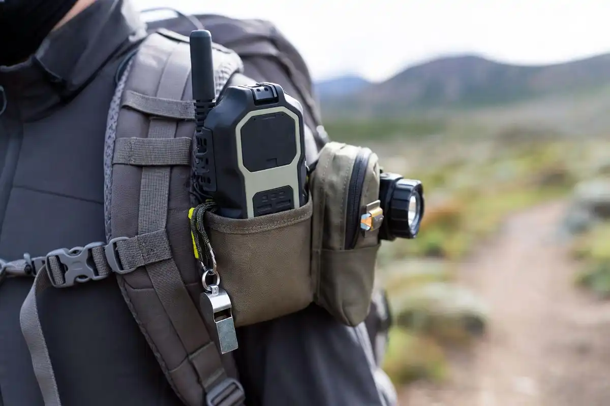 satellite messenger whistle and headlamp attached to backpack strap