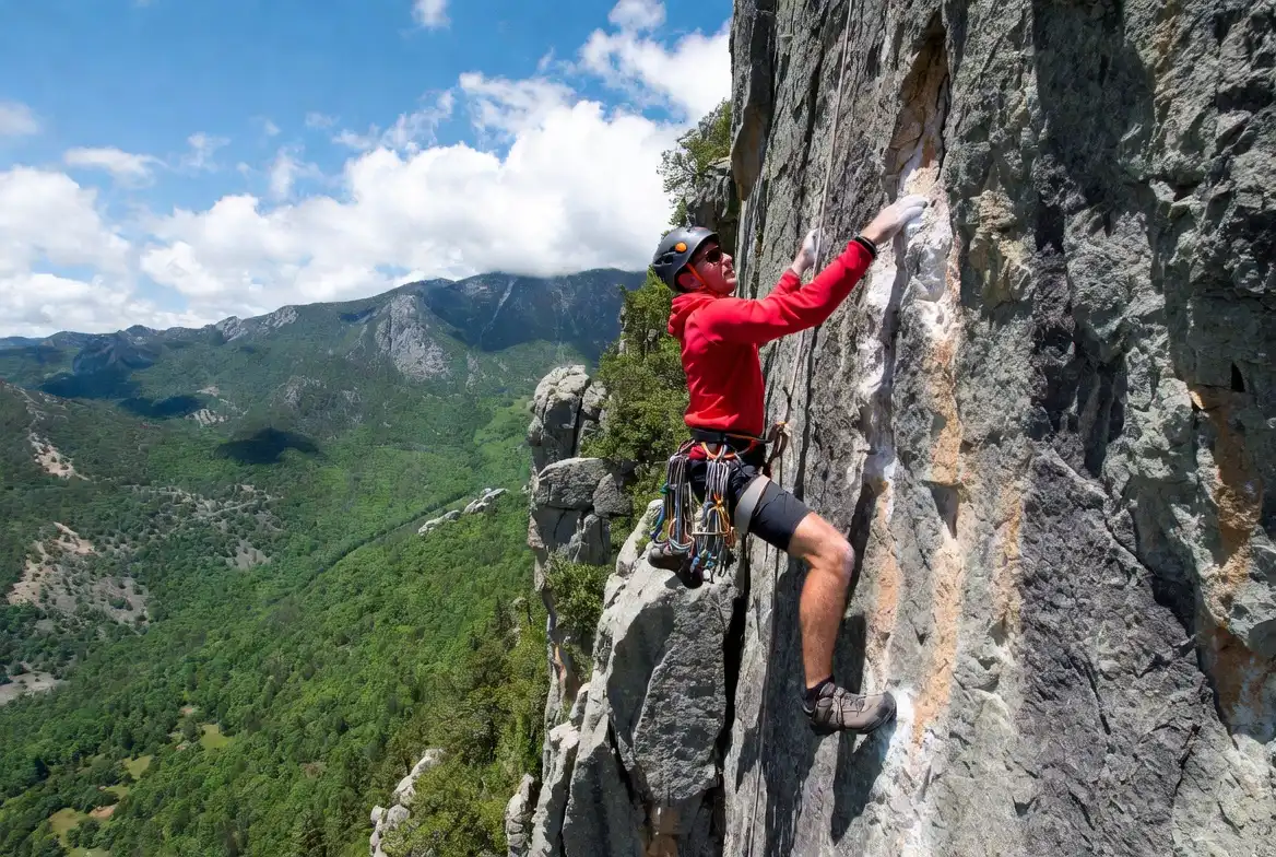 climber with technical gear on rock face covered by specialist adventure policy