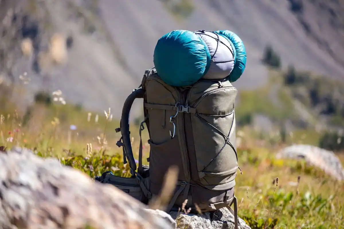 Sleeping bag secured to a hiking backpack with a bungee cord hooked to Daisy chain loops