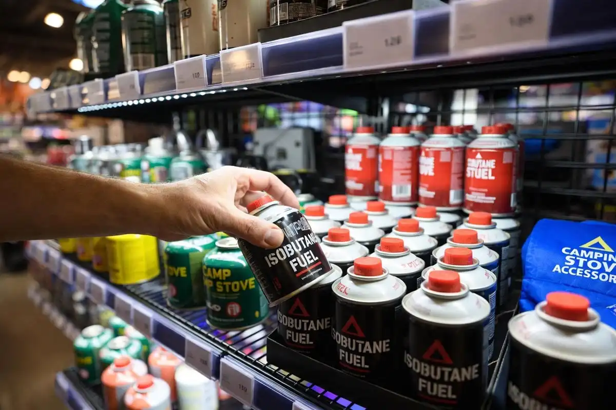 camper picking up fuel canister from outdoor gear store shelf