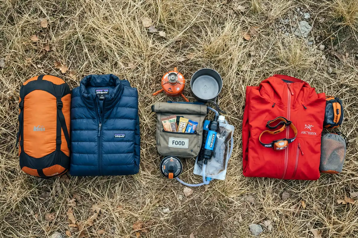 camping gear laid out and sorted into three groups on grass before packing