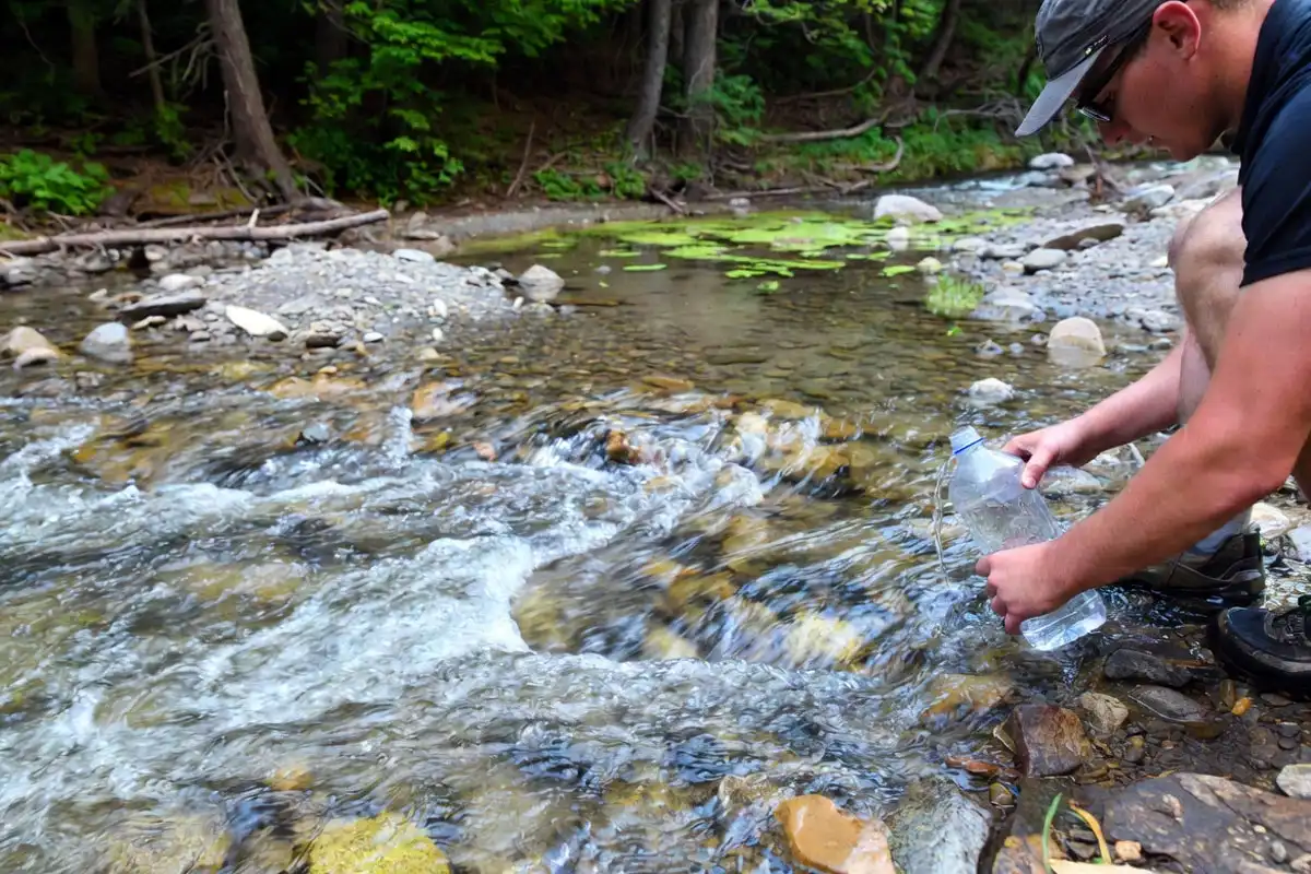 hiker collecting water from a flowing creek
