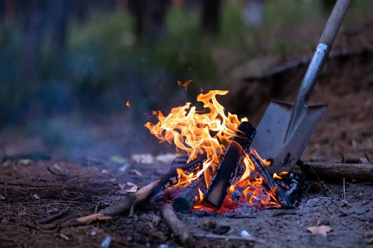 glowing hardwood coals spread in a circle inside a campfire ring ready for Dutch oven baking