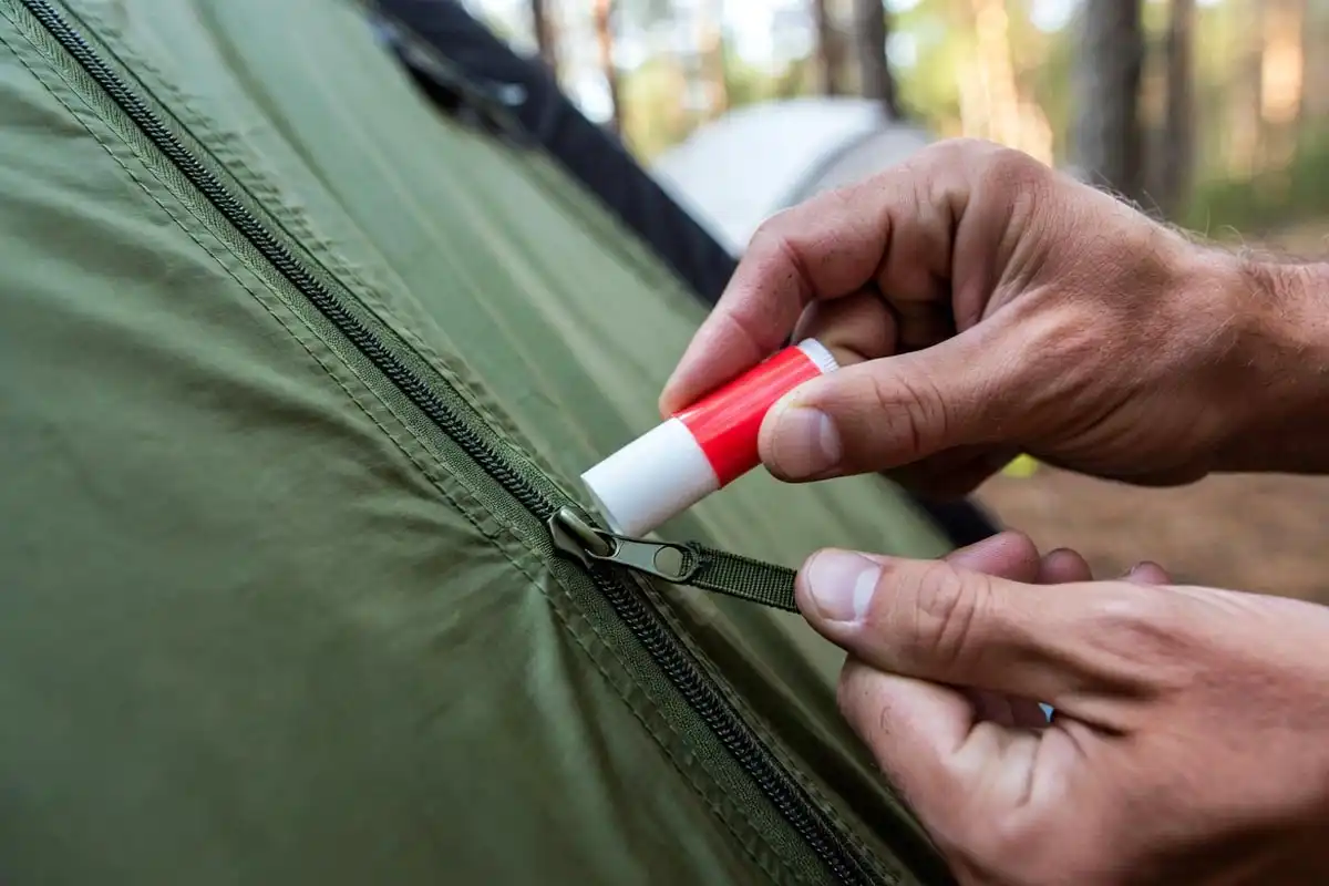 camper rubbing lip balm on tent zipper teeth to lubricate and free stuck slider