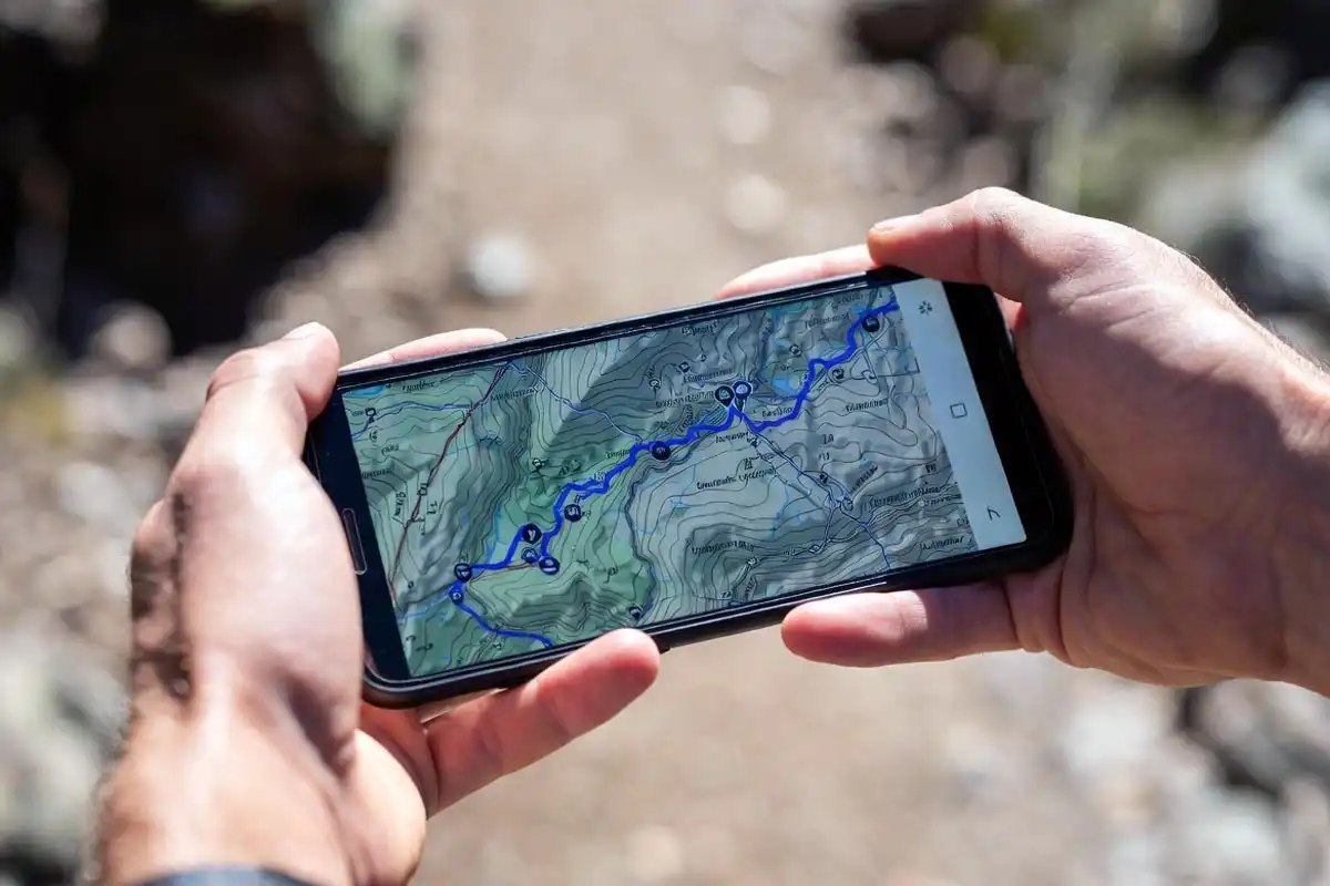 smartphone displaying topo map with marked hiking route on trail