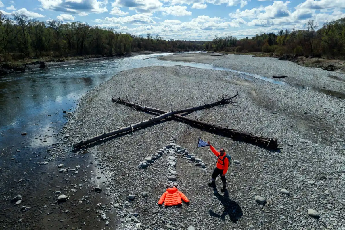 large ground X and arrow made from logs and stones