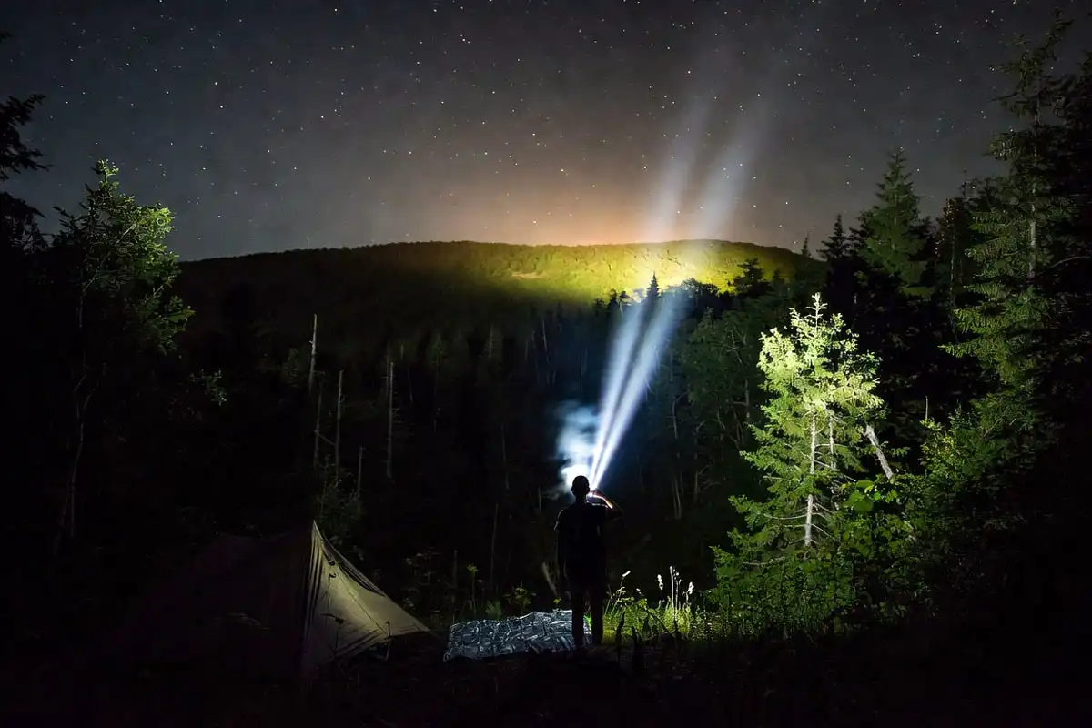 camper flashing a headlamp from a safe clearing at night