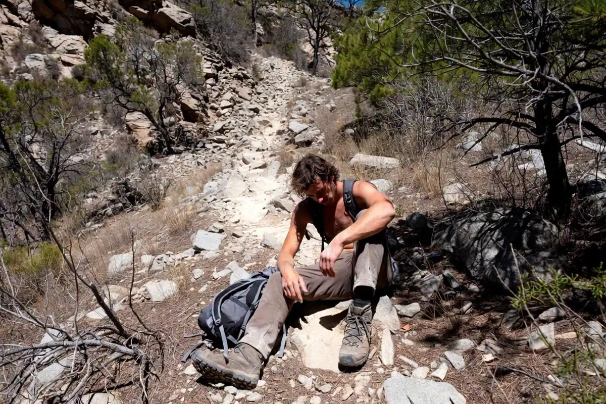 hiker resting on rocky mountain path showing signs of trail fatigue