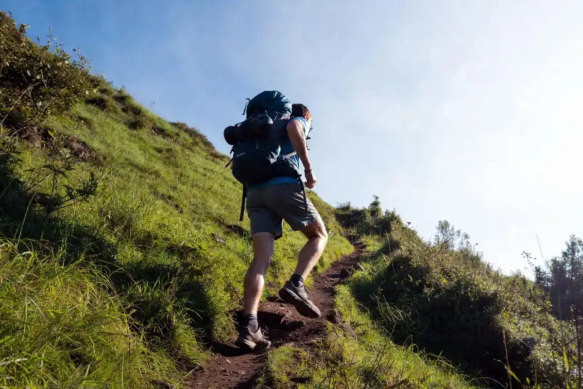 person training on steep grassy hill with loaded daypack to build trail endurance