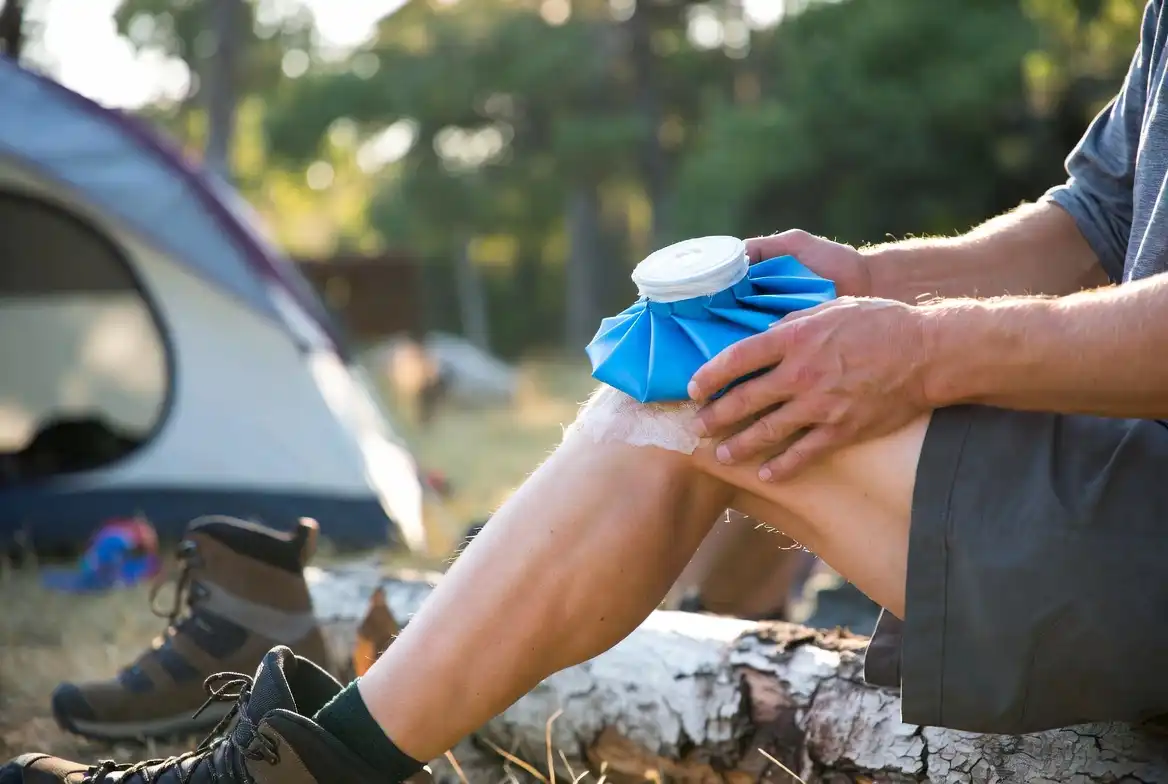 hiker applying ice pack to knee at campsite after long descent