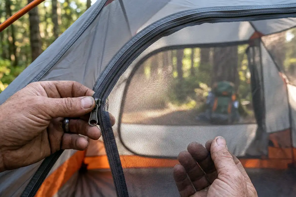 Camper checking tent mesh netting for small tears