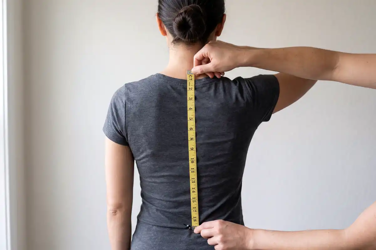 person measuring torso length from neck to hip bone with a flexible tape