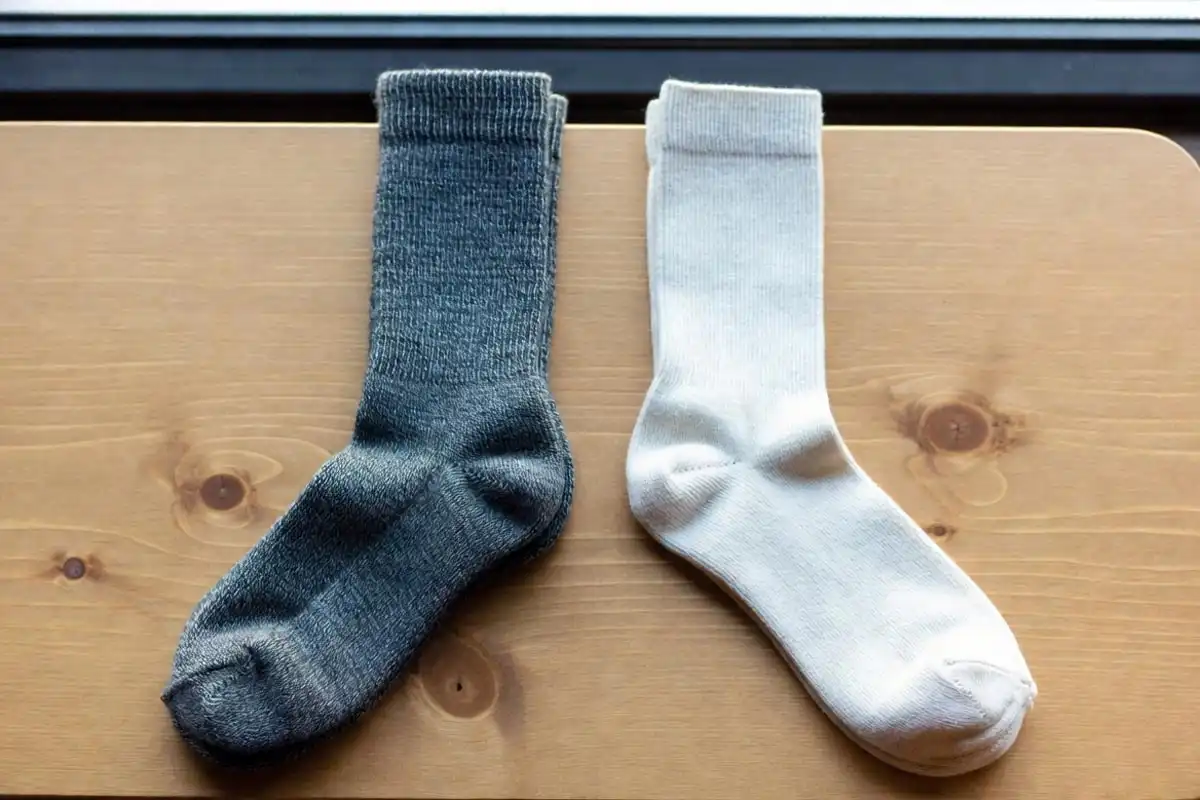 merino wool hiking sock next to cotton sock on wood surface