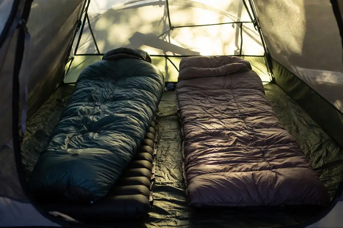 Mummy sleeping bag and backpacking quilt side by side on a sleeping pad