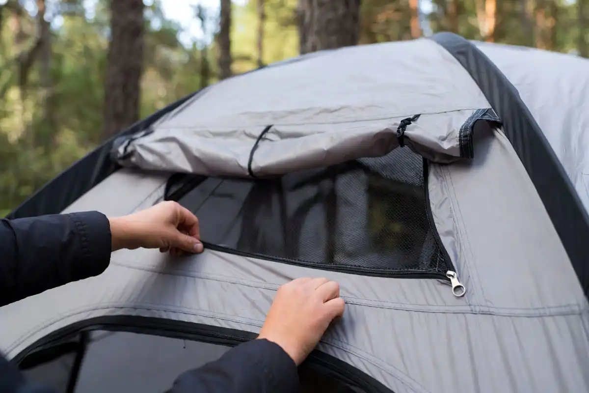 camper opening the mesh roof vent on a double wall tent