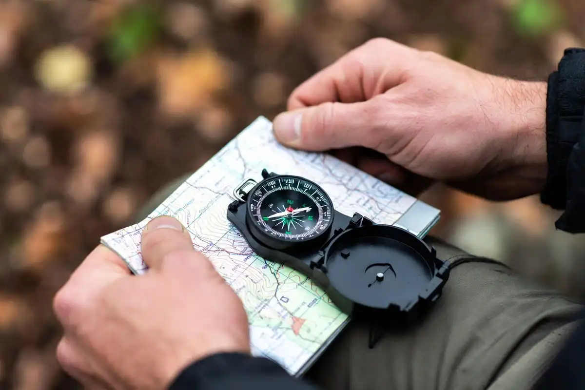 hands aligning compass with topo map grid lines