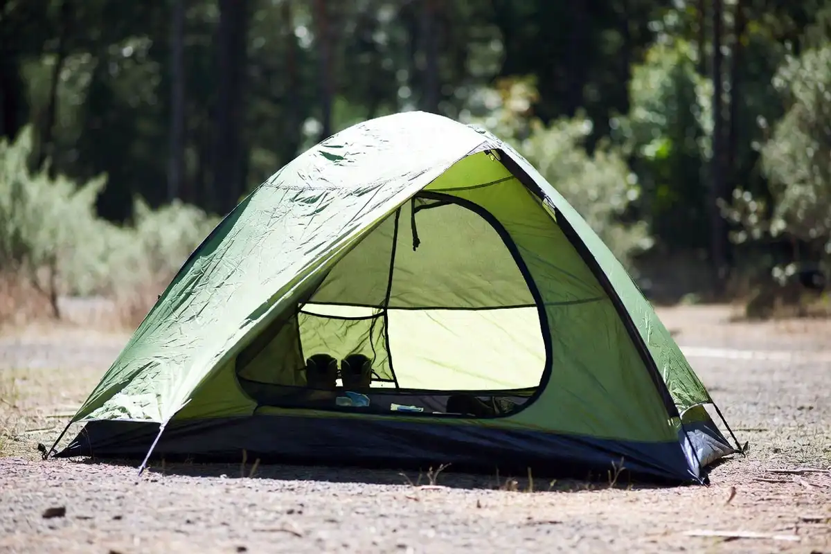 fully zipped camping tent set up on clear ground away from rocks and fallen logs
