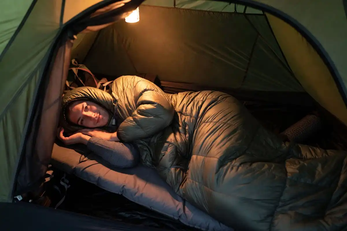 Camper sleeping on side inside a roomy sleeping bag in a tent