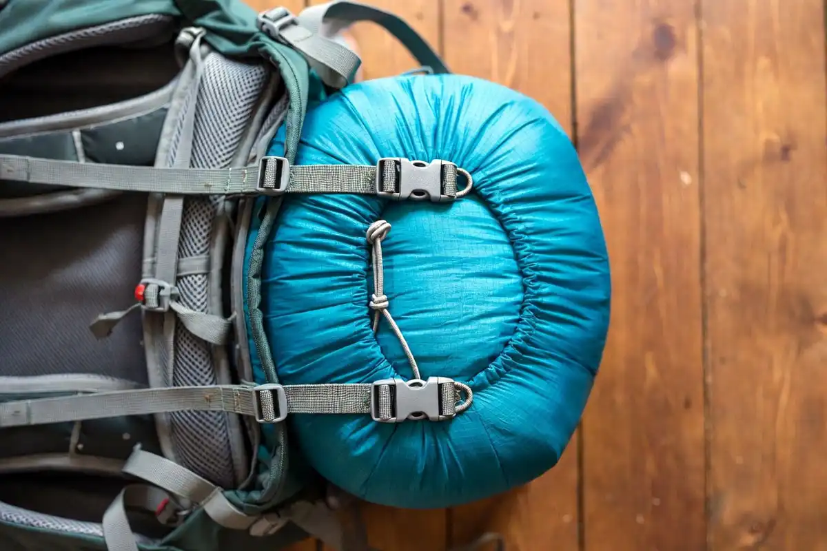 Compressed sleeping bag attached to backpack bottom straps through stuff sack loops