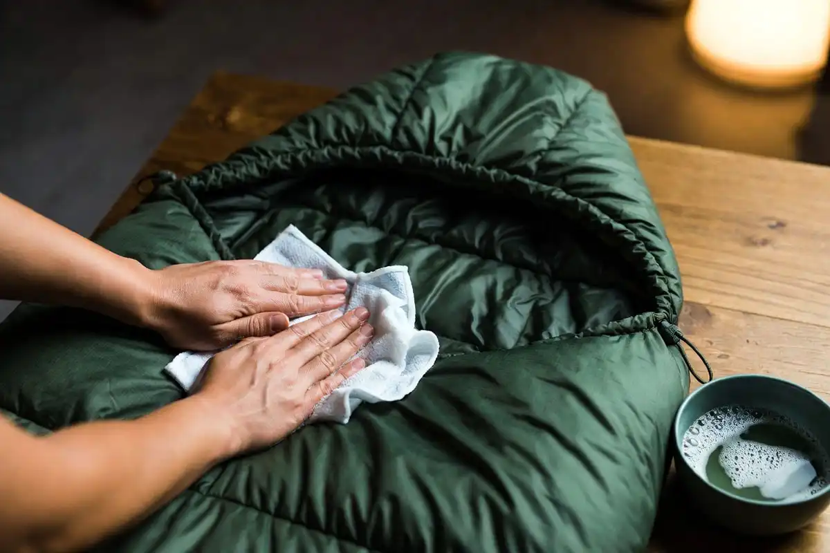 Camper spot cleaning a sleeping bag collar with a damp cloth