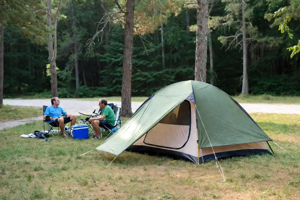 sunny summer campsite with tent and green forest surroundings