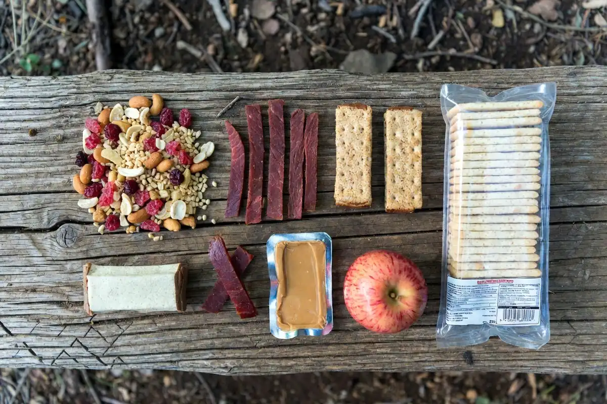 trail mix jerky energy bars and fruit laid out as hiking snacks on the trail