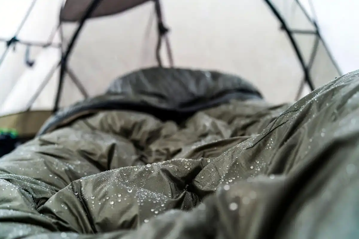 Water droplets beading on a sleeping bag shell fabric inside a damp tent