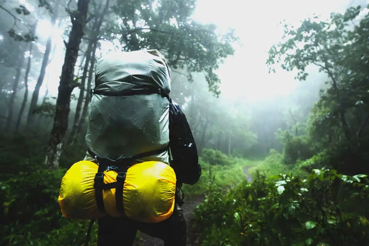 Waterproof compression sack protecting a sleeping bag on a backpack during rain on a Forest trail