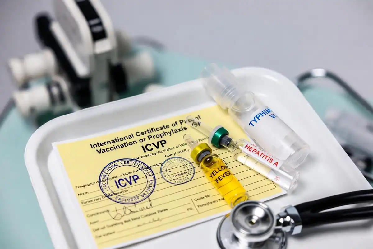 ICVP yellow card beside yellow fever hepatitis A and typhoid vaccine vials on medical tray