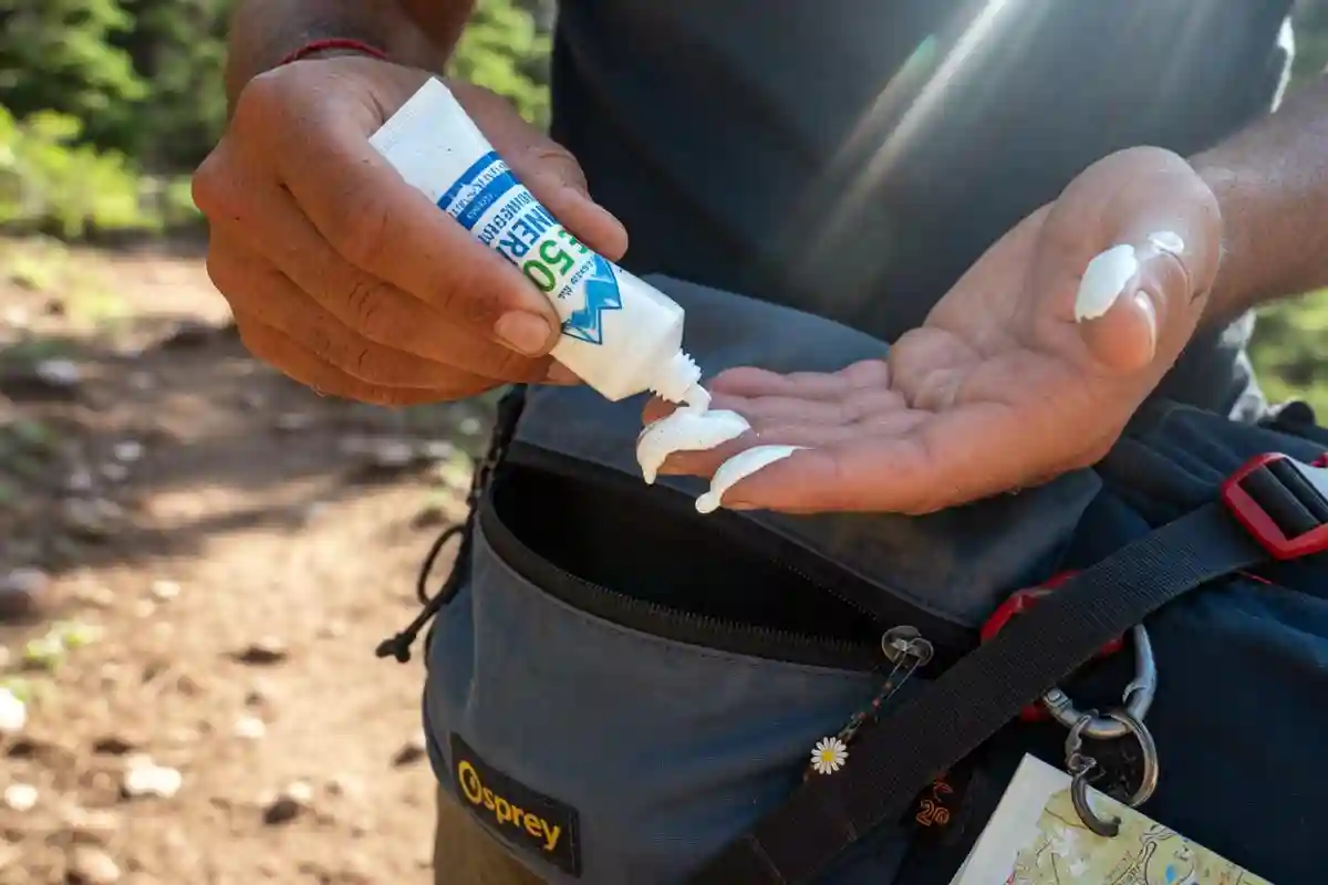 Hiker squeezing mineral sunscreen onto fingers on the trail