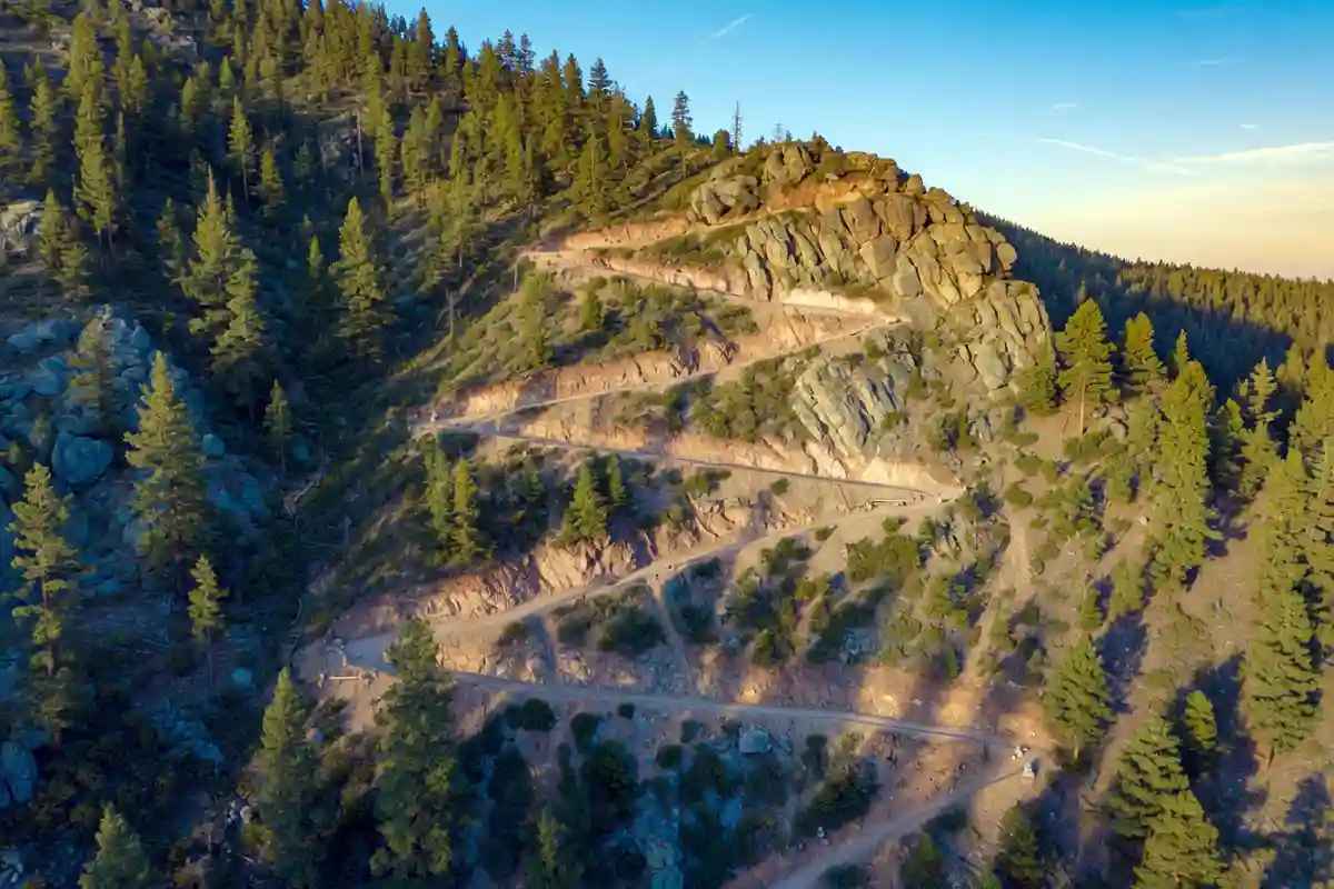 Steep switchback trail cutting up a forested mountain slope
