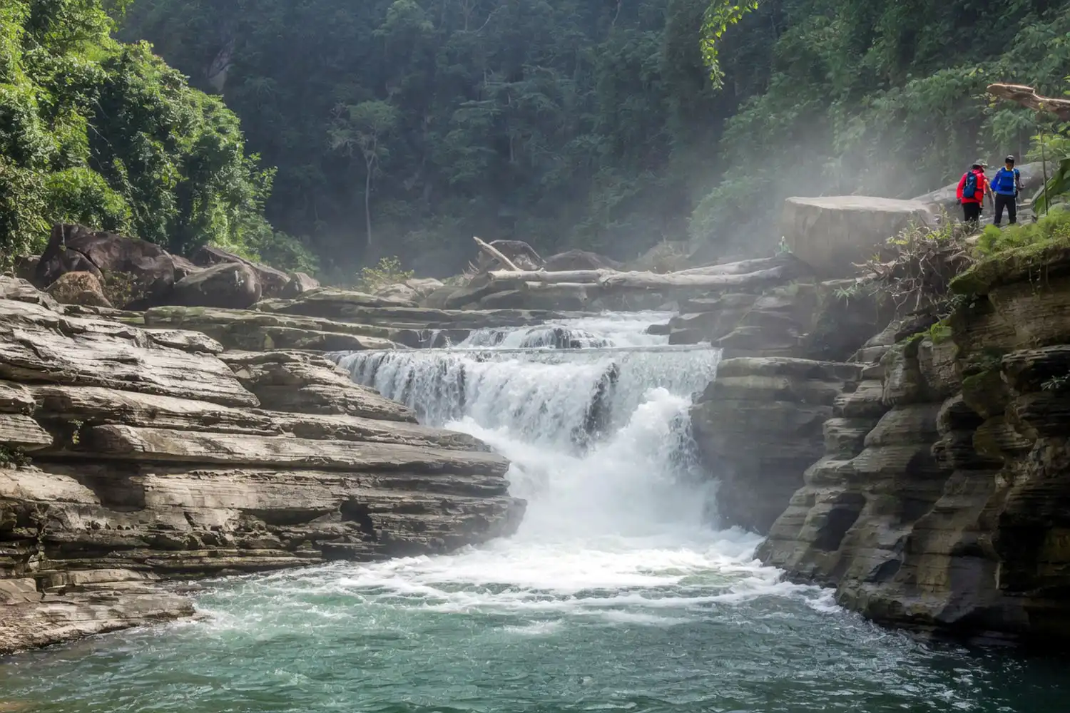 Amiakhum Waterfall in Bandarban, Bangladesh, with water rushing over wide rock shelves and white spray