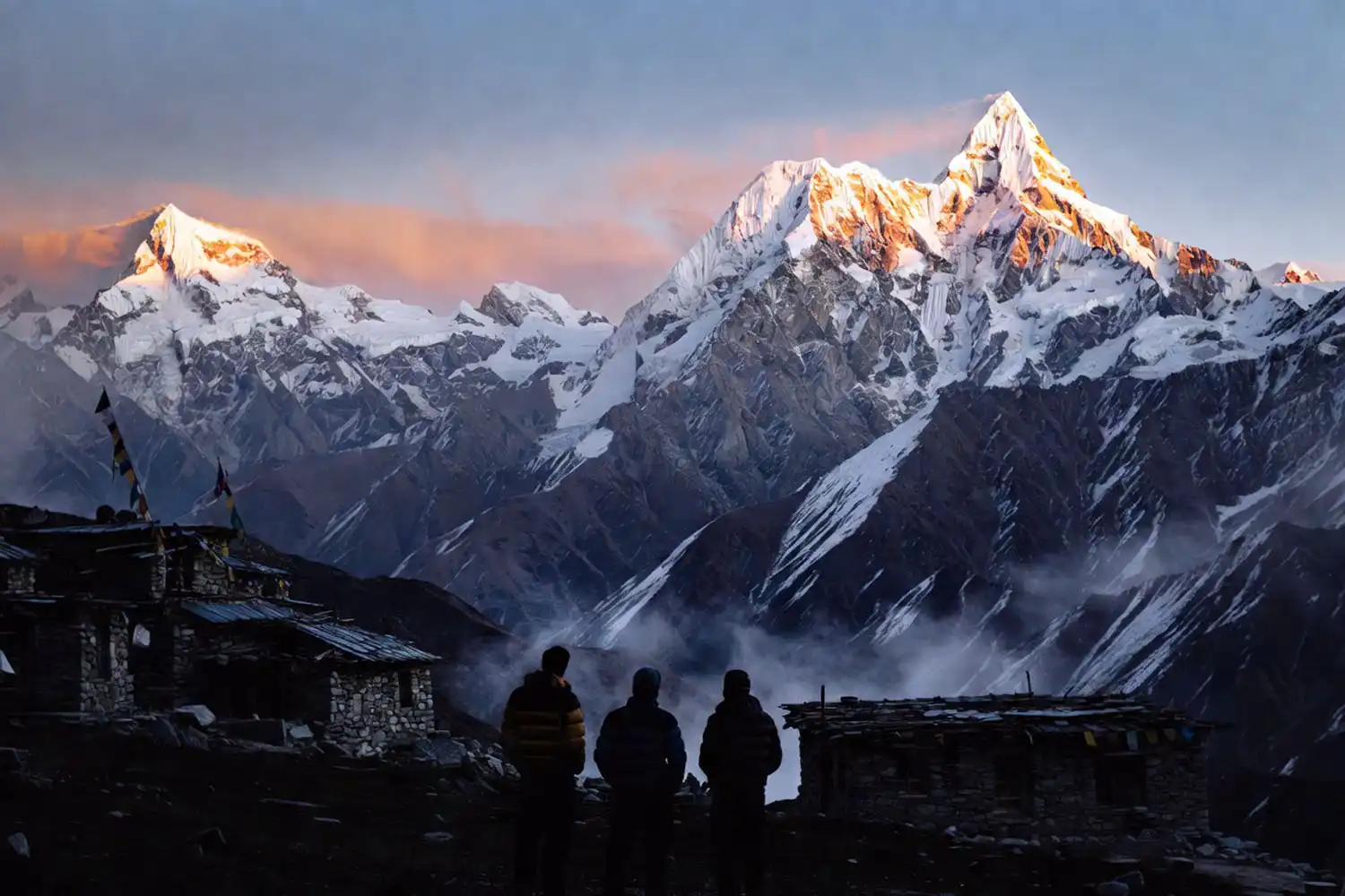 Trekkers watching sunrise at Annapurna Base Camp with Machhapuchhre and Annapurna South peaks lit golden in the background