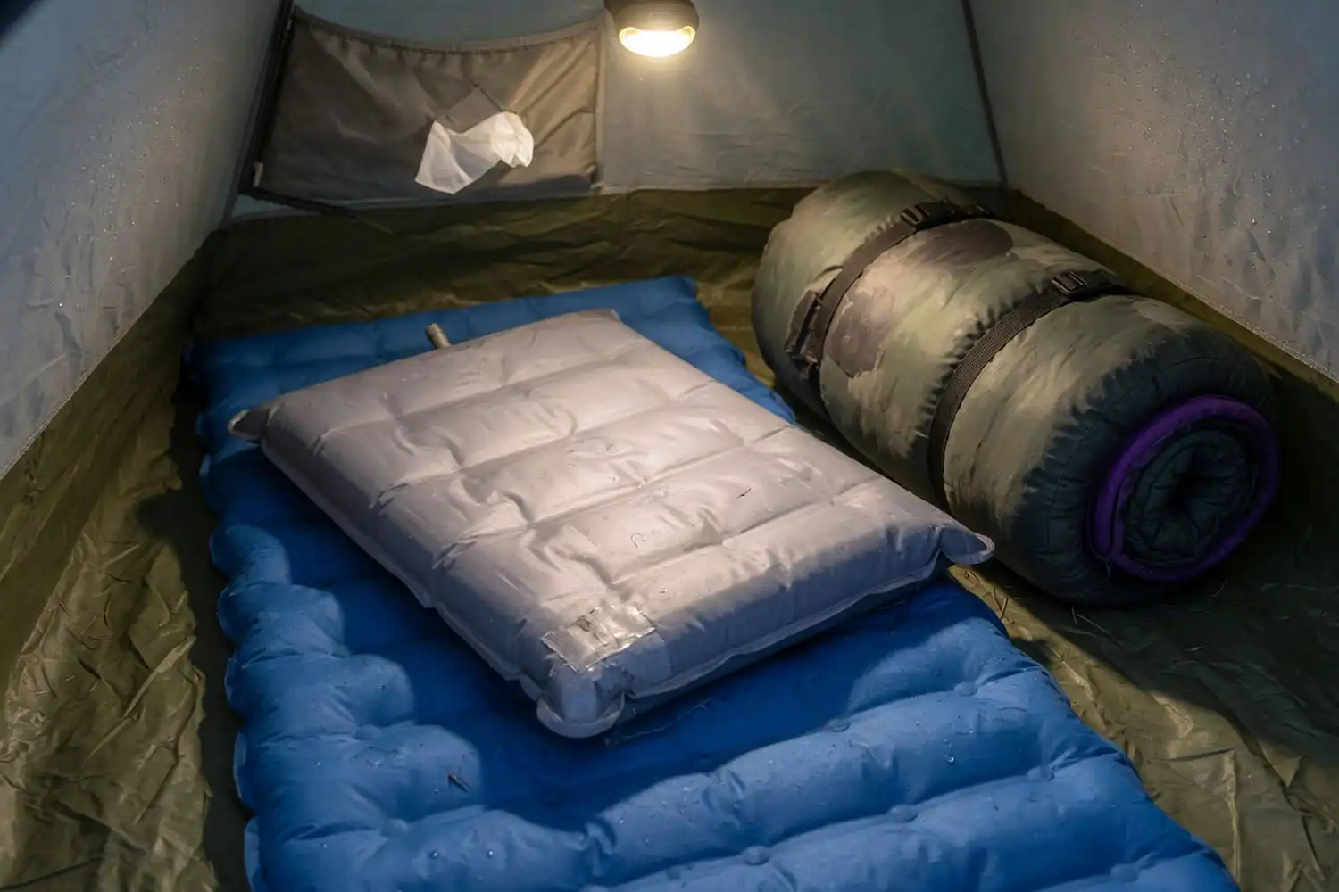 Close-up of a blue closed-cell foam pad layered under a gray insulated air pad inside a winter tent floor