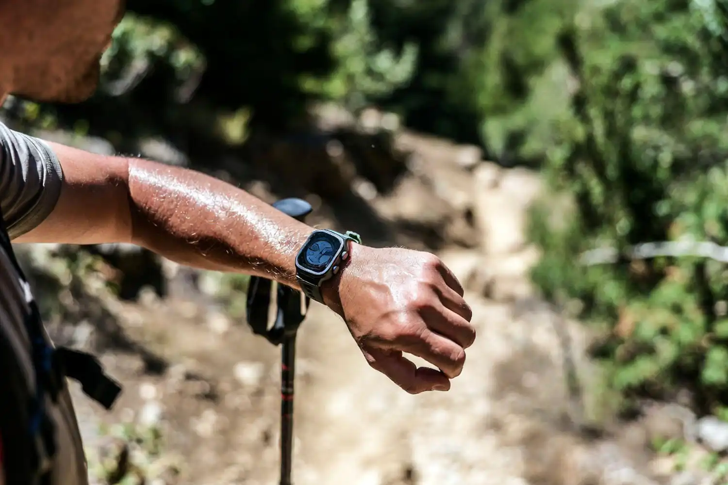 Hiker pausing on a steep trail to check heart rate on a smartwatch during a moderate climb