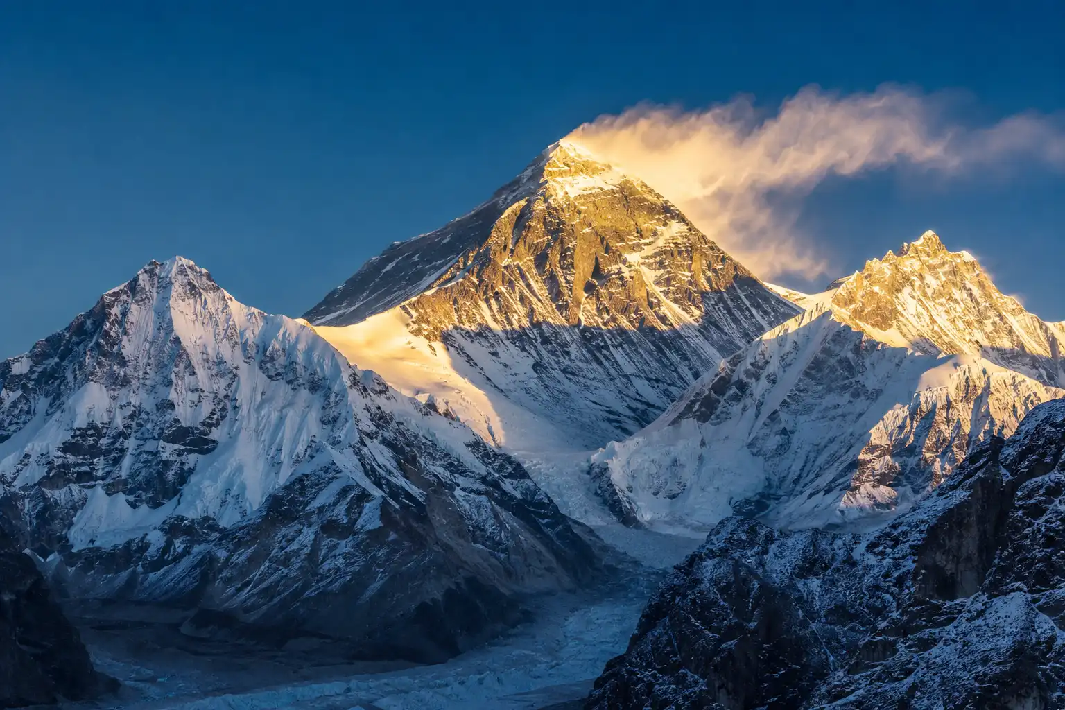 Mount Everest south face at sunrise with snow plume blowing off the summit and climbing route visible up the Lhotse Face