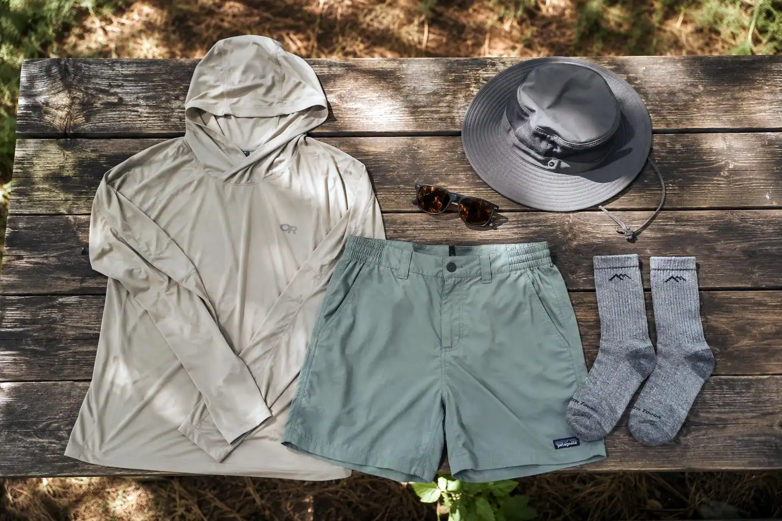 Summer camping clothing laid out on a wooden picnic table
