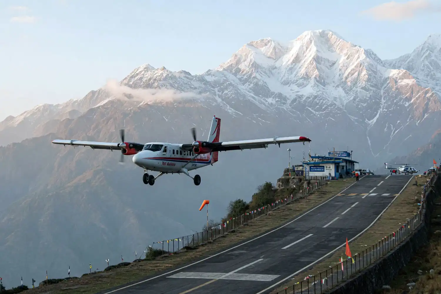 Small Twin Otter aircraft approaching the short uphill runway at Lukla airport with Himalayan peaks