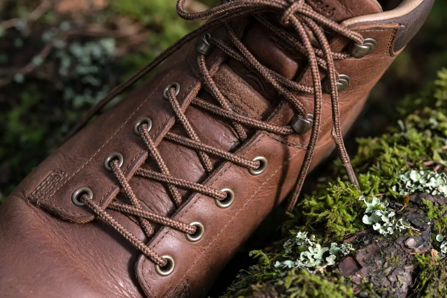 Close up photorealistic view of window lacing on a hiking boot showing the open gap where laces skip the pressure point