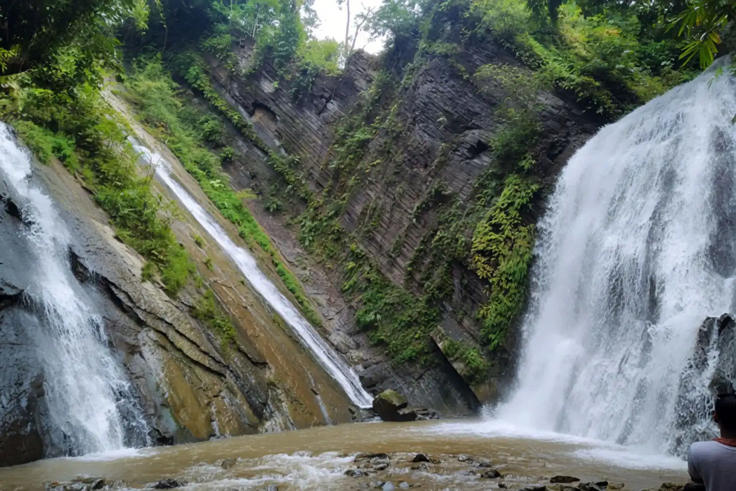 he twin streams of Damtua Waterfall falling over a steep rock face in the green hills of Alikadam, Bandarban